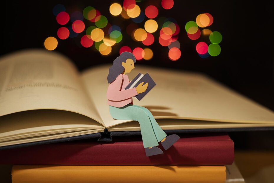 Image représentant une personne en papier assise en train de lire sur une pile de livres. En haut de sa tête se trouve des confettis lumineux de couleurs.